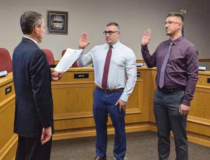 Village solicitor Paul Skaff, left, administers the oath of office to new police officers Nathan Hall-Berkey and Austin Krueger.