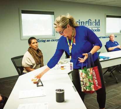 Holland Principal Nelle Ratliff distributes honey to board members during her presentation on the school’s bee observation hive.