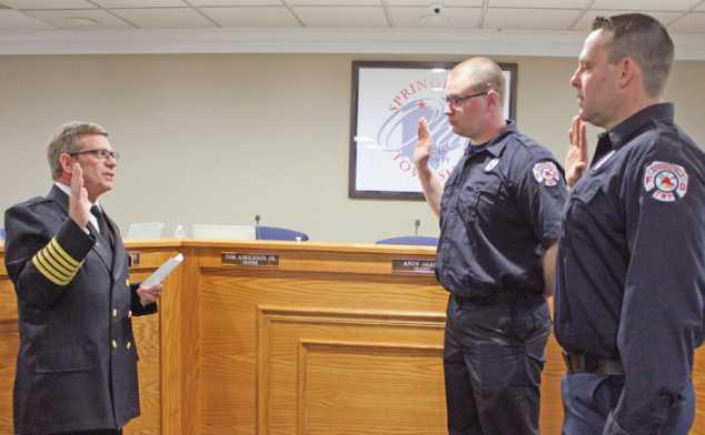 Fire Chief Barry Cousino, left, swears in firefighter/paramedics Trevor Ashbaugh, background, and Marc Wismer, foreground, to full-time duty, effective March 6. “These gentlemen are very dependable, reliable and trustworthy,” the chief said. Both men previously worked part time for the department.
